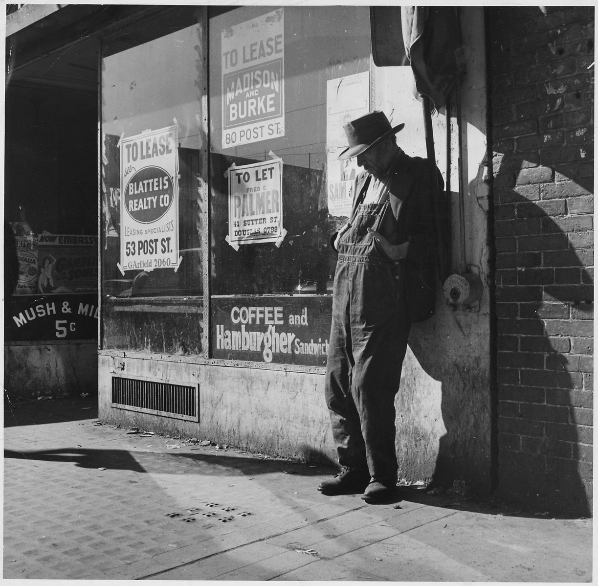 photograph Great Depression era man leans against vacant store window