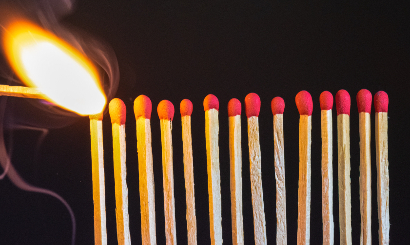 photograph of a row of matches about to catch fire one by one